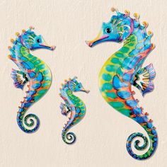 two colorful seahorses standing next to each other on a white wall with swirly designs