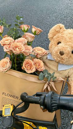 a teddy bear sitting on top of a bike with flowers in it's basket