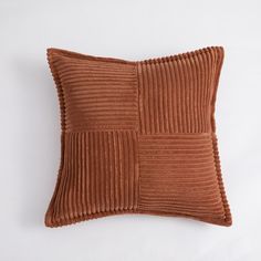 a brown pillow with pleated squares on the front and sides, sitting on a white surface