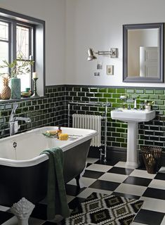 a black and white checkered floor bathroom with green tiles on the walls, an old fashioned bathtub