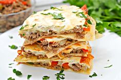 a stack of mexican quesadillas stacked on top of each other with meat and vegetables