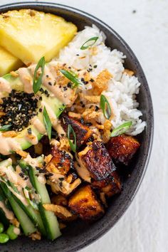 a bowl filled with rice, meat and veggies next to pineapples