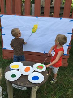 two young boys are painting on paper plates