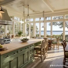 a large kitchen with lots of windows and green cabinets, along with wooden flooring