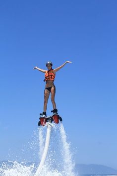 a person on water skis jumping in the air with their arms out and hands outstretched