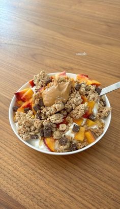 a bowl filled with granola and fruit on top of a wooden table