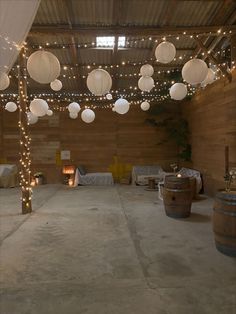 the inside of a barn decorated with lights and paper lanterns