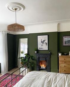 a bedroom with green walls and a fireplace in the corner next to a bed that has a white bedspread on it