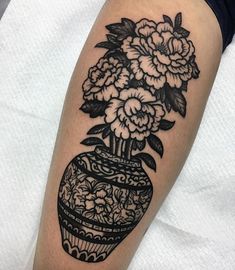 a black and white tattoo with flowers in a vase