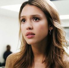 a close up of a person with long hair and wearing a brown sweater in an office setting