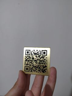 a hand holding up a gold colored qr code sticker