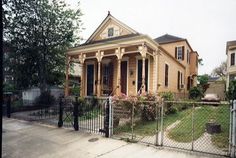 an old house with flowers in the front yard and fenced in area next to it