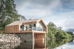 a wooden structure sitting on top of a river next to a lush green forest covered hillside