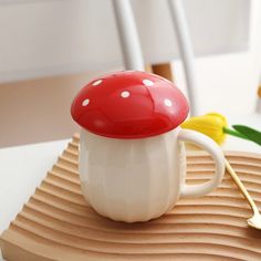 a red and white mushroom shaped coffee cup on top of a wooden tray with flowers