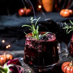 two glasses filled with liquid sitting on top of a table next to small pumpkins