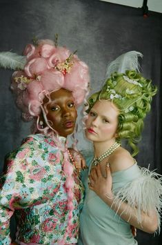 two women with green hair and pink wigs are posing for a photo in front of a black backdrop