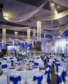 the banquet hall is decorated with blue and white linens, sashes, and centerpieces