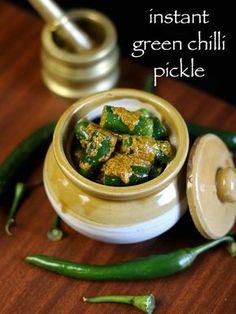 green chilli pickle in a small bowl on a wooden table next to other vegetables