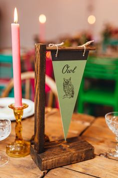 a wooden table with two candles on it and an owl flag hanging from the top