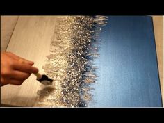 someone using a brush to paint the edge of a piece of wood with silver glitter