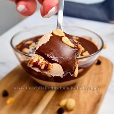 a person scooping ice cream out of a bowl with nuts on the side,