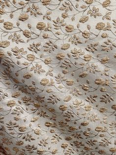 a white and gold floral print fabric with small flowers on the side, closeup