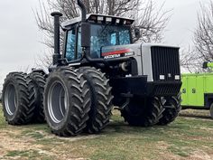 a large tractor parked in the grass near some trees