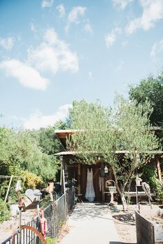 a bride's dress hanging on the back of a tree in front of a house