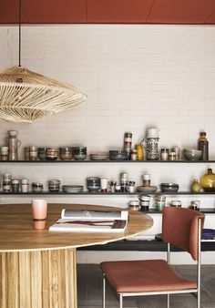 a wooden table with two chairs next to it and shelves full of jars on the wall