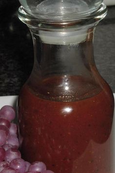 a bottle of sauce next to some grapes on a plate