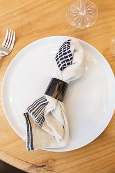 a white plate topped with two napkins on top of a wooden table next to a fork and knife