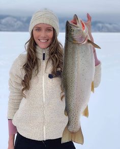 a woman holding a fish in the snow