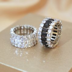 two wedding rings sitting next to each other on top of a wooden table with diamonds