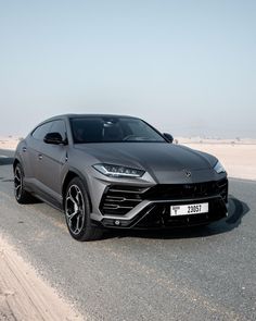 a grey lamb urus is parked on the side of the road in front of an empty parking lot