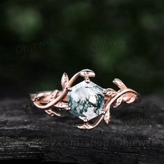 a close up of a ring on top of a piece of wood with leaves around it