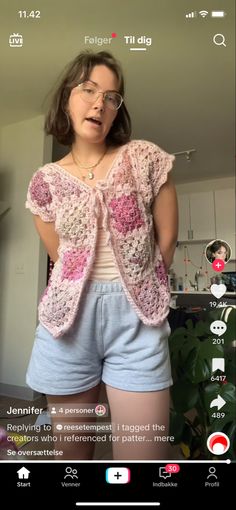 a woman wearing shorts and a pink crochet top is standing in front of a mirror