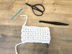 a crocheted object sitting on top of a wooden table next to a pair of scissors