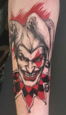 a joker tattoo on the leg of a person with a red and black checkered clown face