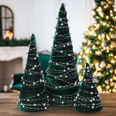 three green christmas trees sitting on top of a wooden table