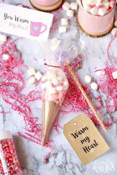 pink and white cupcakes with marshmallows in the middle on a marble table