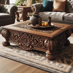 an ornately carved coffee table with fruit on top sits in front of a couch