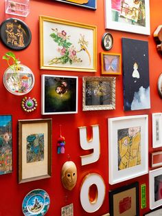 a red wall covered in lots of framed pictures and art on it's sides