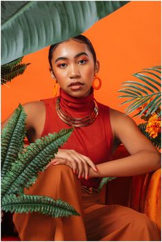 a woman sitting in front of a green plant