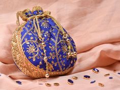 Blue Potli Bag with Pearl Handle Strap With its classy zari work and a pearl handle strap all in gold this Blue Potli Bag is ideal for this wedding season. Fabric Raw Silk Color Royal Blue Embroidery Zari Work in Gold Size amp Dimensions Height - 8 inWidth - 7.5 inDepth - 1.5 in Strap Pearl Handle Strap Closure Tasseled Drawstring Compartments Single compartment Care Wipe with a soft clean amp dry cloth to remove dust When not in use store it in a dust bag for longer product life Avoid liquid ex Elegant Potli Bag With Latkans For Diwali, Gold Zari Work Bag For Diwali, Gold Bag With Zari Work For Diwali, Elegant Festive Potli Bag With Latkans, Gold Bags With Zari Work For Diwali, Bollywood Style Gold Shoulder Bag With Zari Work, Elegant Festival Potli Bag, Festive Party Potli Bag With Openable Detail, Festive Gift Potli Bag