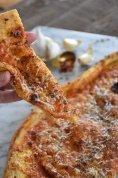 a person holding up a piece of pizza with cheese and other toppings on it