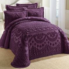 a bed with purple bedspreads and pillows