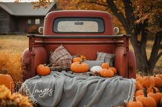 an old red truck with pumpkins in the bed and plaid blanket on it's back