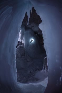 a man standing in an ice cave at night with his flashlight glowing through the hole