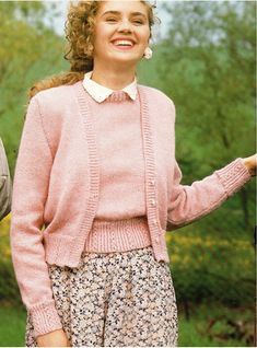 a woman wearing a pink sweater and flowered skirt with her hands in her pockets