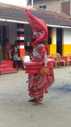 a woman is dressed up in red and white clothing while walking down the street with an elaborate headdress